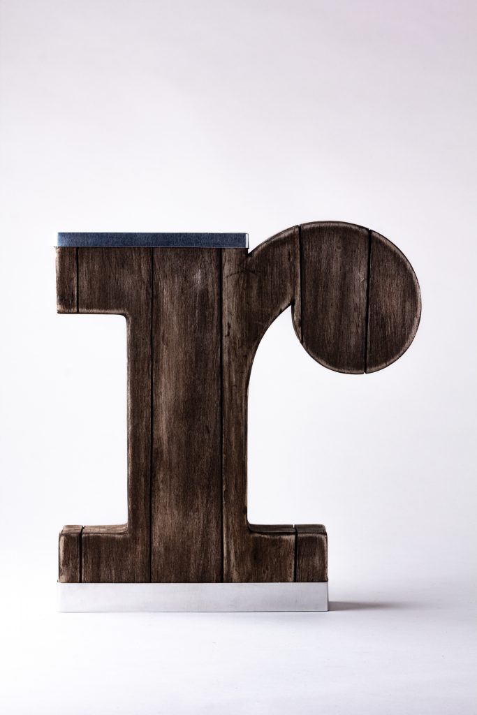 Front view of experimental packaging for the letter R, made of wood, and metal bands